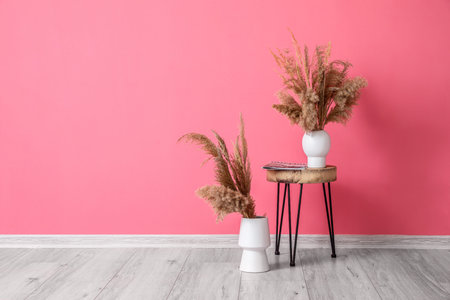 Table and vases with dry reeds near color wallの写真素材