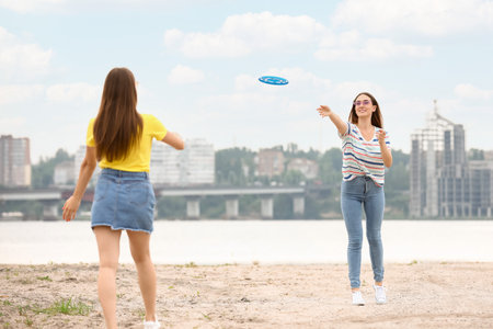 Beautiful young women playing flying disc near the riverの写真素材