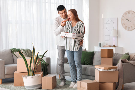 Happy young couple eating tasty pizza on moving day