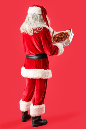 Santa Claus holding boxes with tasty pizza on red backgroundの写真素材