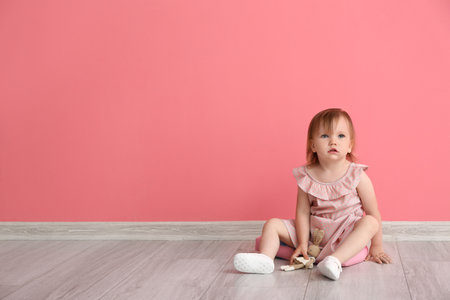 Cute baby girl sitting near color wallの写真素材