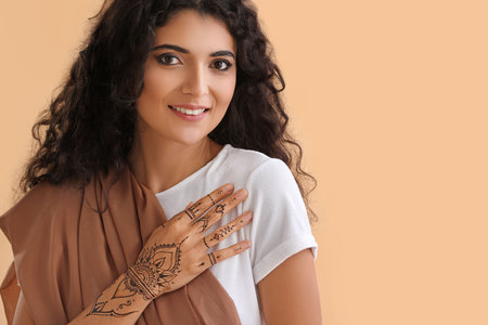 Beautiful Indian woman with henna tattoo on color backgroundの写真素材