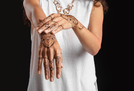 Beautiful Indian woman with henna tattoo on dark backgroundの写真素材