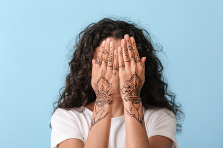 Beautiful Indian woman with henna tattoo on color backgroundの写真素材