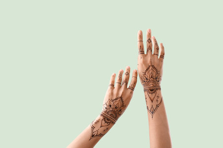 Female hands with henna tattoo on color backgroundの写真素材