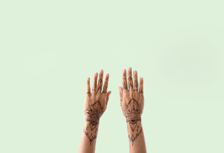 Female hands with henna tattoo on color backgroundの写真素材
