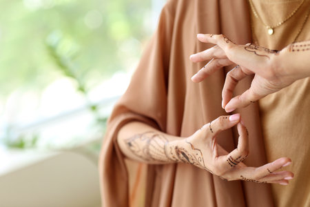 Beautiful Indian woman with henna tattoo at home, closeup