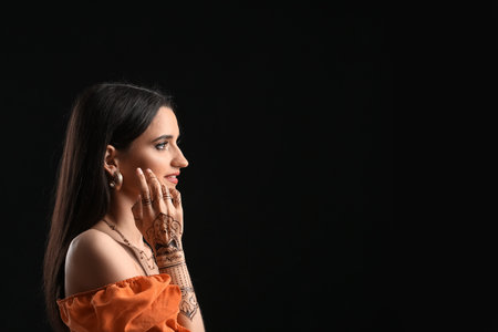 Beautiful Indian woman with henna tattoo on dark background