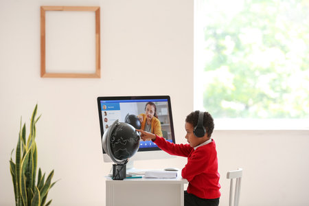 Little African-American boy studying Geography online at home
