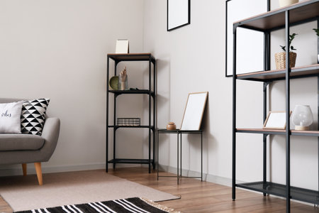 Shelf unit with decor and blank photo frames near light wall