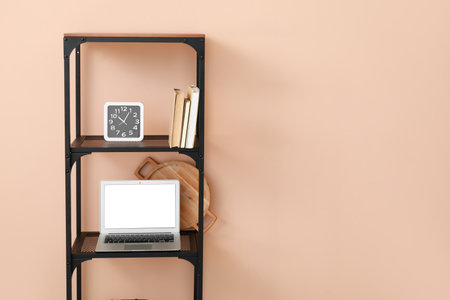 Stylish shelf unit with decor and modern laptop near color wallの写真素材