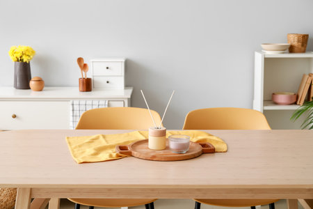 Dining table with reed diffuser and candle in interior of light roomの写真素材