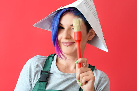 Female painter with paper hat and brush on red backgroundの写真素材