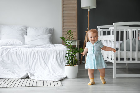 Cute baby girl learning to walk in the bedroomの写真素材