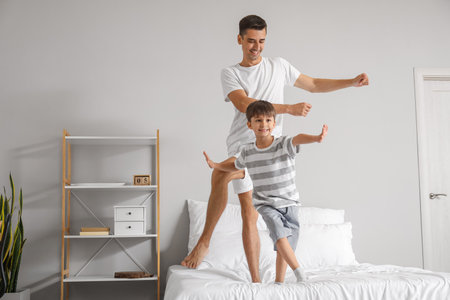 Man and his little son dancing in the bedroomの写真素材
