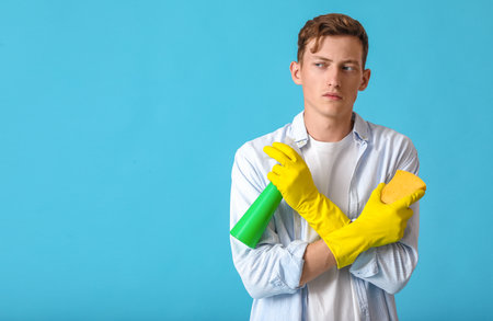 Handsome man with sponge and detergent on blue backgroundの写真素材