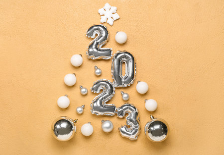 Christmas tree made of figure 2023 and balls on beige background