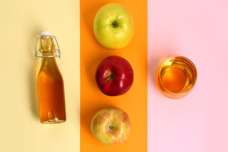 Composition with ripe apple, bottle and glass of fresh juice on color backgroundの写真素材