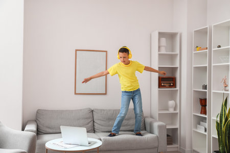 Funny little boy with laptop learning to dance at homeの写真素材
