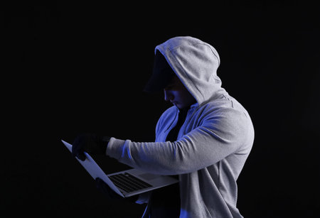 Hacker with laptop on dark background