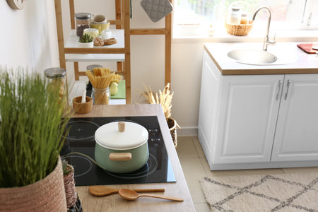 Electric stove with pot and utensils on counter in modern kitchenの写真素材