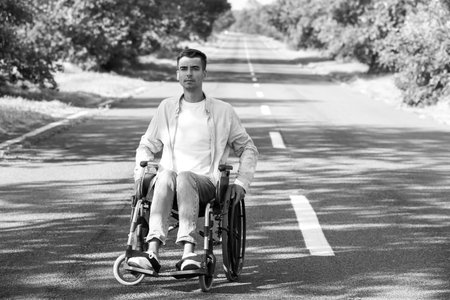 Black and white portrait of a young man in a wheelchair outdoors