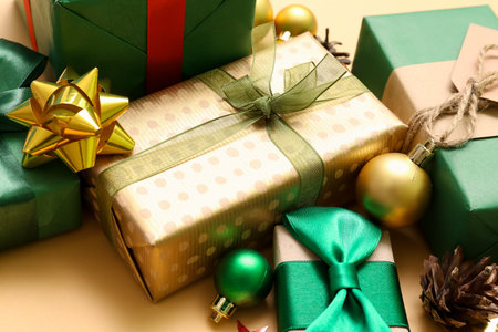 Gift boxes with Christmas balls on beige background, closeup
