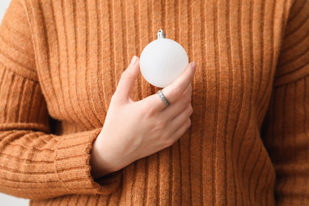 Woman with white Christmas ball on light background, closeupの写真素材