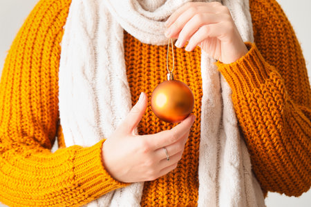 Woman with orange Christmas ball on light background, closeupの写真素材