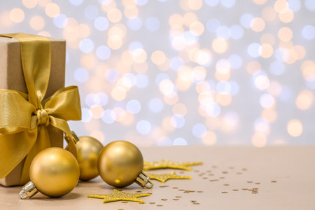 Golden Christmas balls with gift on table against blurred lightsの写真素材
