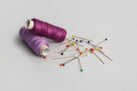 Thread spools and ball pins on gray background