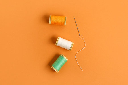 Thread spools with needle on color background