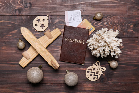 Passport with toy airplane, coral and Christmas decor on dark wooden backgroundの写真素材