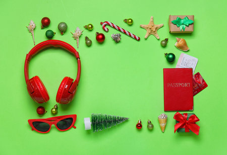 Frame made of travel accessories with Christmas decor and seashells on green backgroundの写真素材