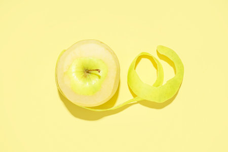 Peeled juicy apple on yellow backgroundの写真素材