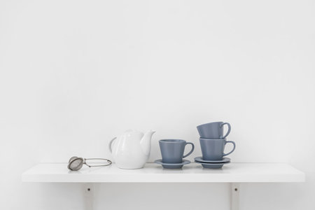 Tea set on shelf near light wallの写真素材