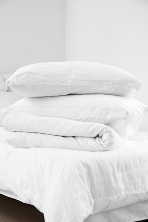 Stack of pillows and blanket on comfortable bed in light bedroomの写真素材