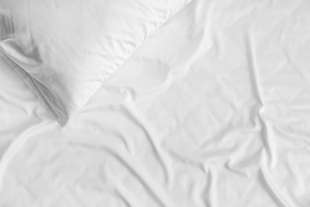 White bed sheet and soft pillow, closeup
