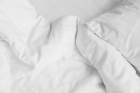 Soft crumpled bedding and pillow, closeup