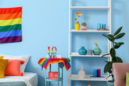 Stylish shelving unit and table with rainbow flags near blue wallの写真素材