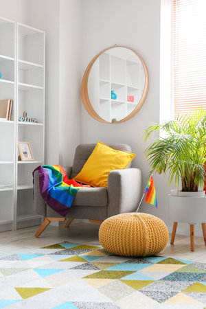 Comfortable armchair with mirror, houseplant and rainbow flags near white wallの写真素材