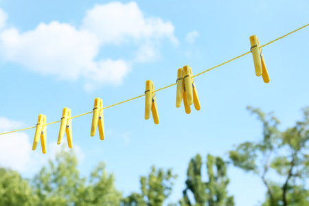 Plastic clothespins hanging on rope outdoorsの写真素材