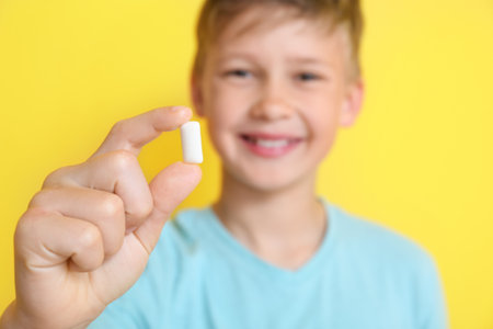 Little boy chewing gum on yellow background, closeupの写真素材
