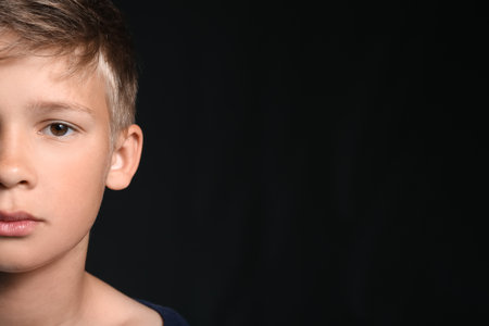 Portrait of little boy on black background, closeup