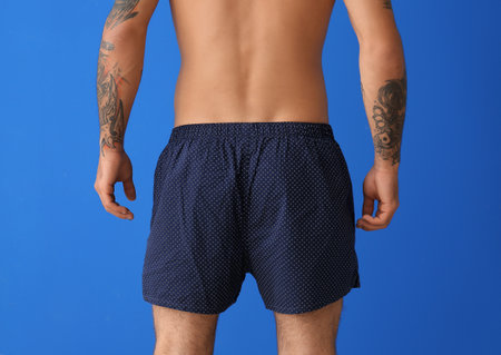 Handsome young man in underwear on color background