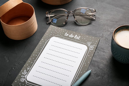 Blank to do list, eyeglasses, cup of coffee and pen on dark table