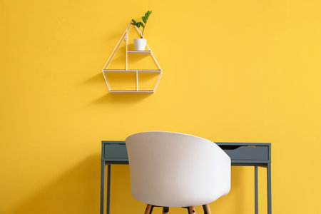 Modern table, chair and shelf with houseplant on color wallの写真素材