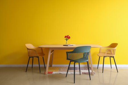 Dining table with flowers and magazine near color wall