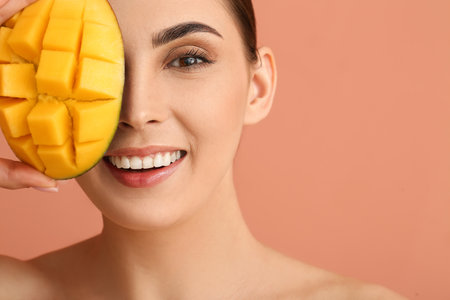 Beautiful woman holding cut mango on color backgroundの写真素材