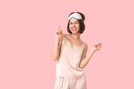Emotional young woman in pajamas and chewing gum on color backgroundの写真素材